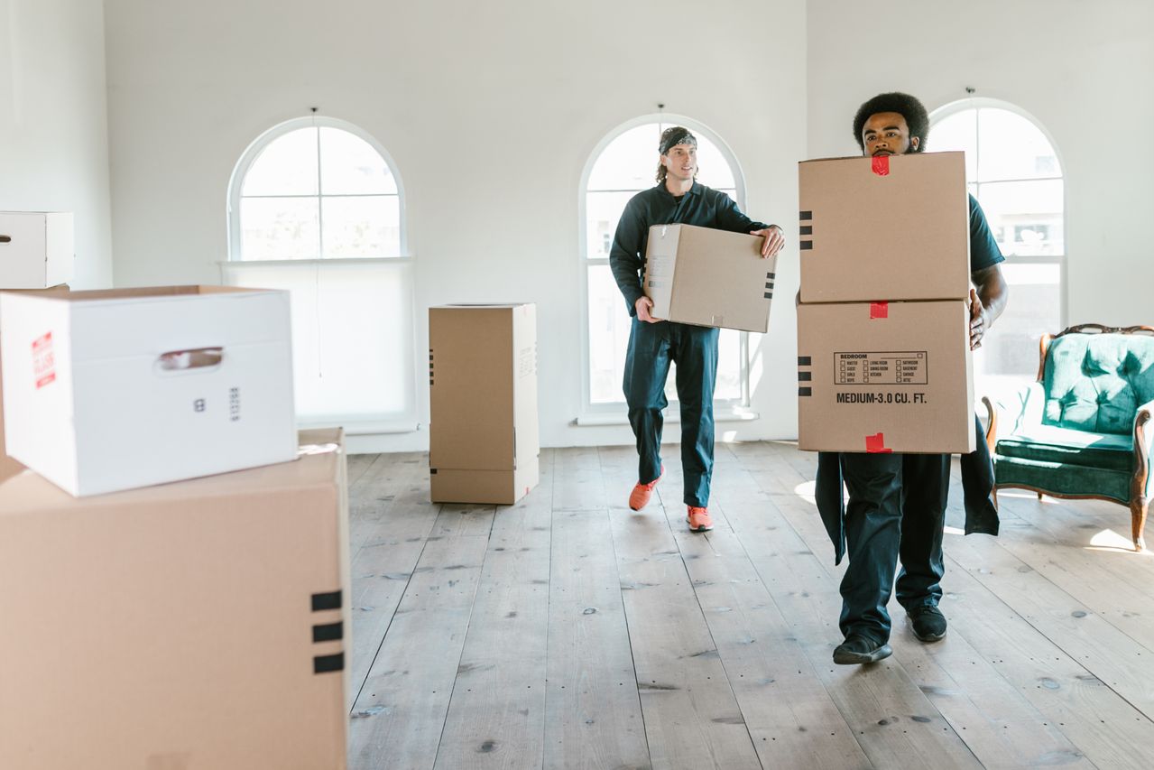 Professional movers carrying labeled cardboard boxes through a home