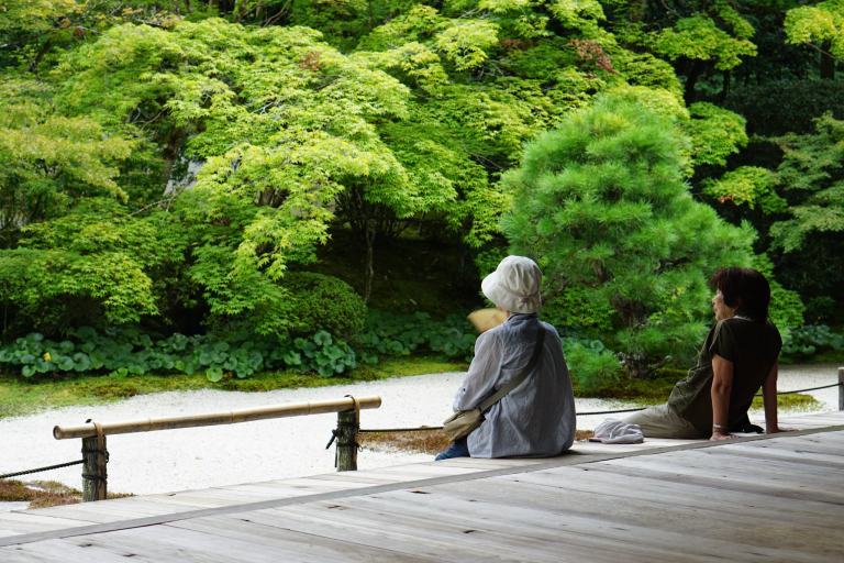 Two women sitting quietly and looking out at a peaceful green garden
