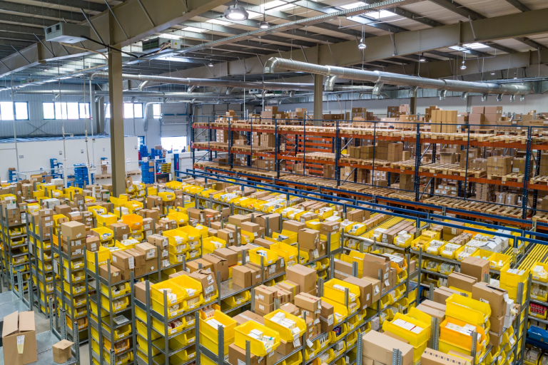 Warehouse with shelves of boxes and yellow storage bins arranged in aisles