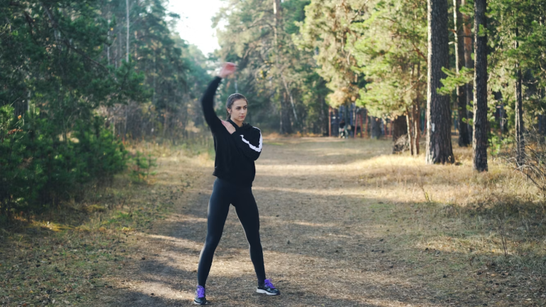 Woman stretching her arms on a wooded trail before exercise