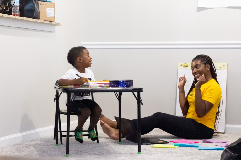 Adult and young child smiling during a one-on-one learning activity at home