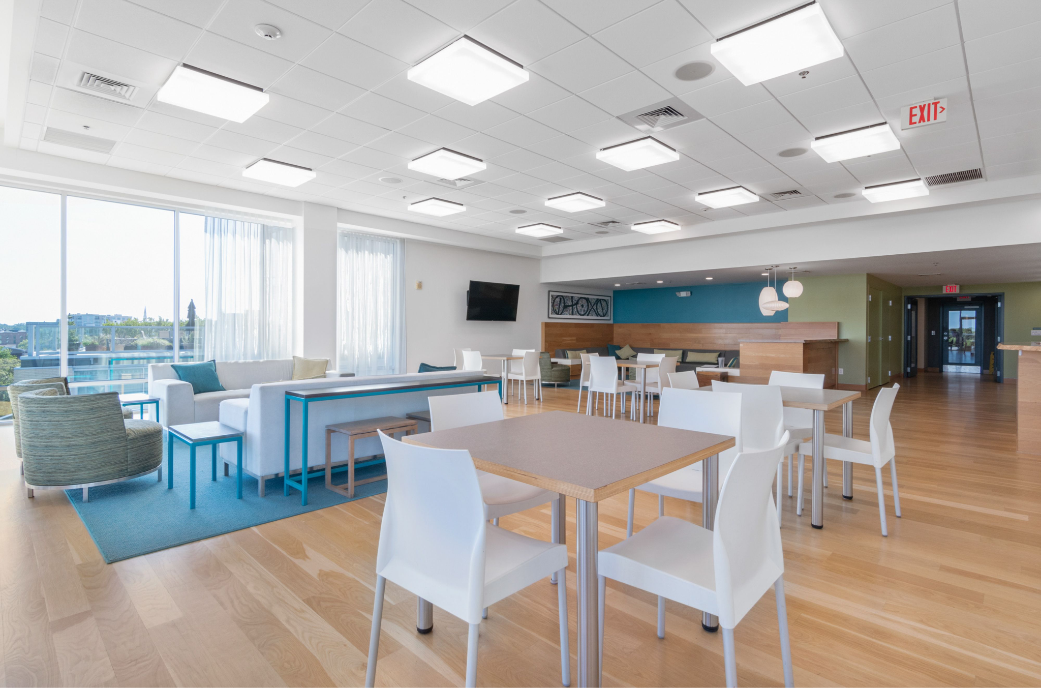 Bright, modern treatment-facility common area with tables, chairs, sofas, and large windows.