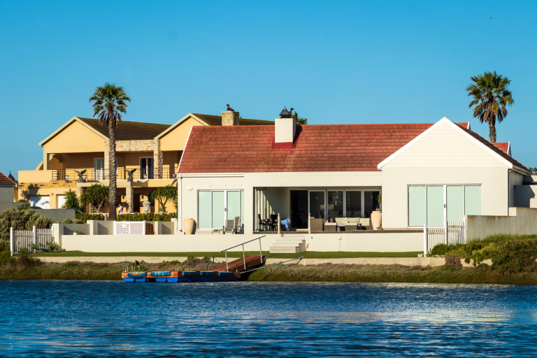 Modern waterfront home with a patio and private dock beside calm blue water