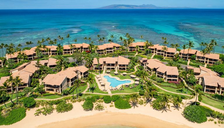 Aerial view of Wailea Ekahi condominiums, tropical landscaping, swimming pools, Keawakapu Beach, and the turquoise Pacific Ocean.