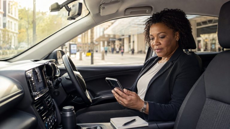 A woman reviewing taxi insurance information on her phone while parked