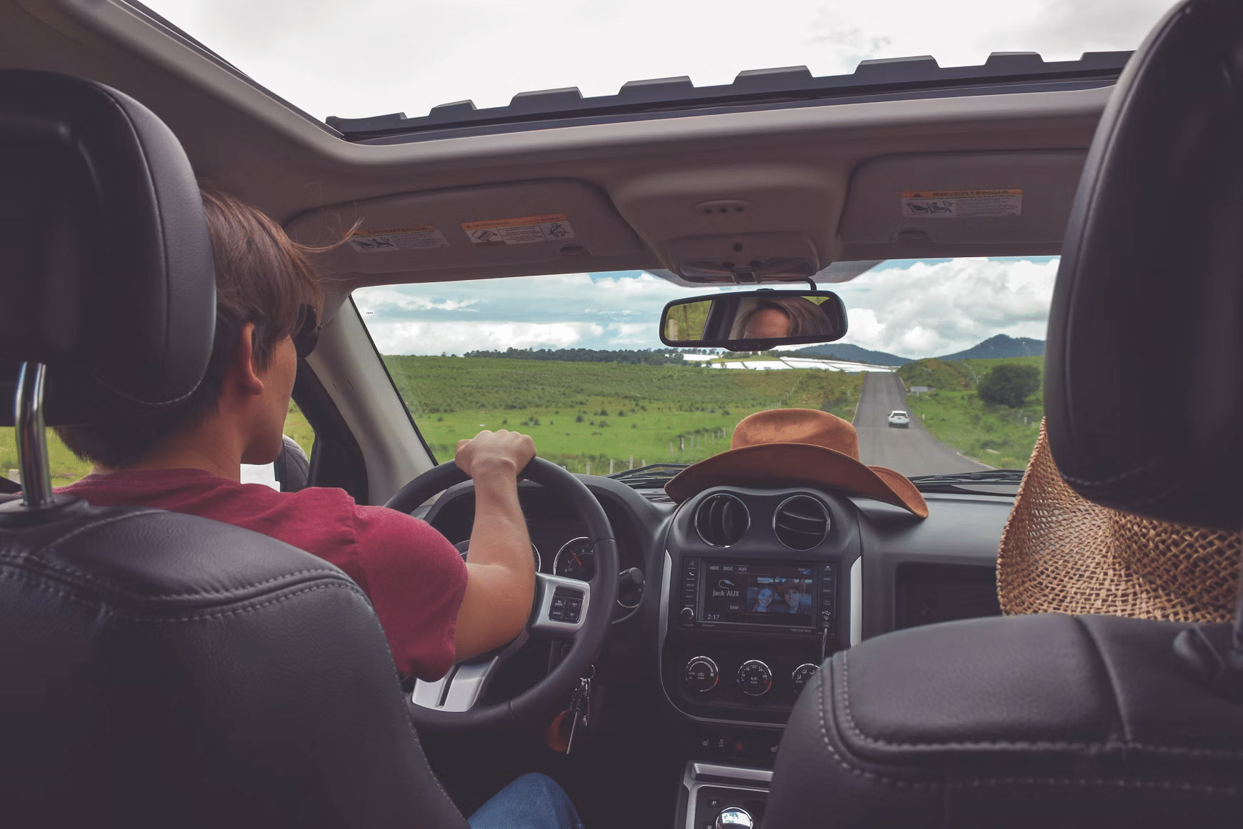 Driver traveling along a rural road as seen from the back seat of a car