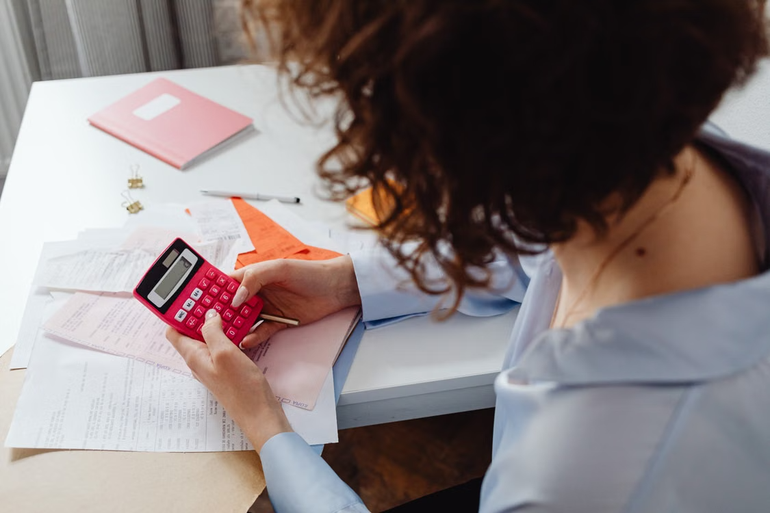 Woman using a calculator to review bills and plan her financial goals